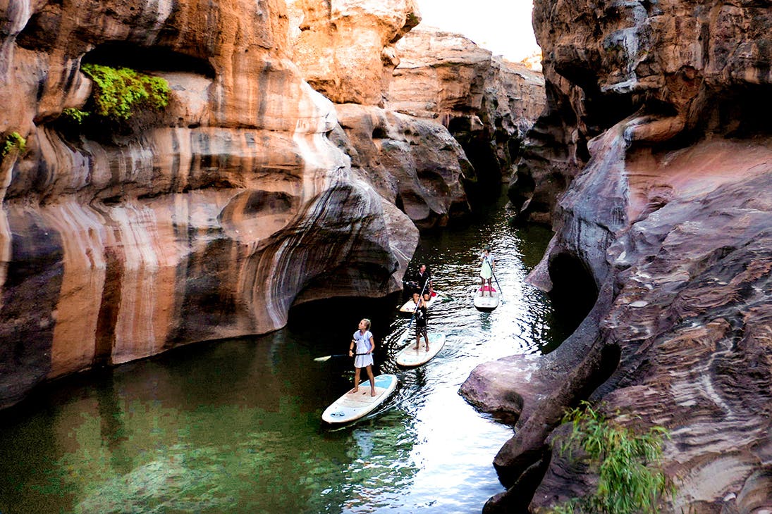 Several people SUP through a deep gorge